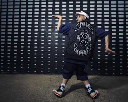 Greenteck in einer Tutting Pose mit dem Rücken zu uns. Man sieht seine gebrandete Jacke