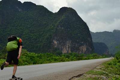 Le globe skater roule en longboard sur une route du Laos au Vietnam par la route frontalière.