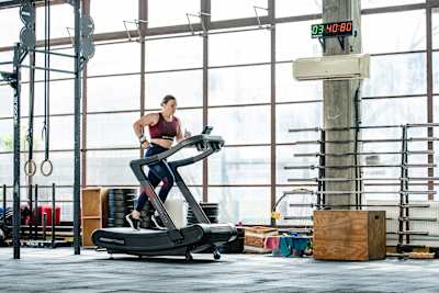 Pro fitness athlete Laura Horváth is running on a treadmill in a gym 