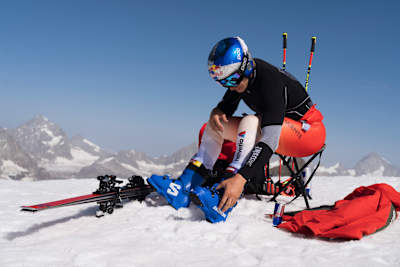 Swiss skiing star Marco Odermatt prepares at a 2025 training camp in Zermatt, Switzerland, surrounded by snowy Alpine peaks and dynamic ski equipment