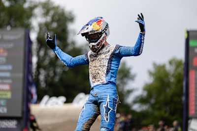 Ronan Dunne freut sich über seinen Sieg beim UCI Mountain Bike World Cup 2025 in Les Gets, Haute-Savoie, Frankreich, und zeigt seine dynamische Energie in einem schlammverschmierten blauen Anzug.