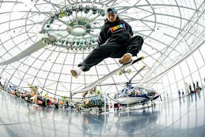 Margielyn Didal macht im Red Bull Hangar einen Kickflip. Über ihr die Glaskuppel des Hangar, hinter ihr steht ein Helikopter.