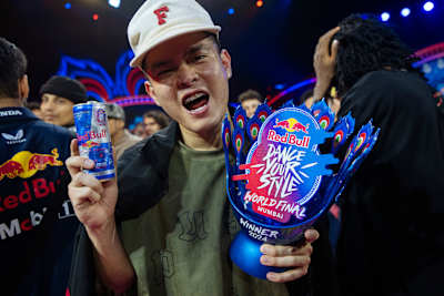 In 2024, MT Pop celebrates at the Red Bull Dance Your Style World Final event in Mumbai, India, holding a Red Bull can and winner's trophy