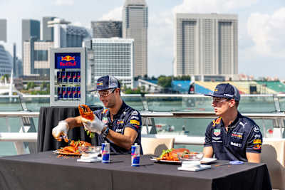 Daniel Riccardo and Max Verstappen attempt to de-shell a crab at a Red Bull event ahead of the Formula One Grand Prix of Singapore in 2018. 