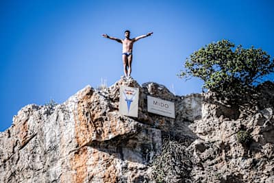 Carlos Gimeno of Spain prepares to dive at the first stop of the 2024 Red Bull Cliff Diving World Series at Lake Vouliagmeni in Athens, Greece, on May 24, 2024.  