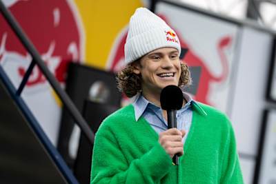 In 2024, Lucas Braathen smiles while speaking at a Red Bull press conference in Salzburg, Austria, wearing a green fuzzy jacket and Red Bull branded beanie.
