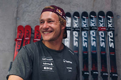 Red Bull athlete Marco Odermatt gears up at the Zermatt training camp in Switzerland, 2025, with Stöckli skis lined up behind him, embodying alpine adventure and peak performance.