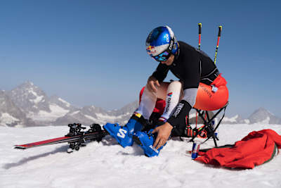 Swiss skiing star Marco Odermatt prepares at a 2025 training camp in Zermatt, Switzerland, surrounded by snowy Alpine peaks and dynamic ski equipment