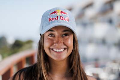 In 2025, Dominique Charrier smiles brightly wearing a Red Bull cap in Chile.
