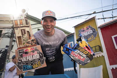 Tomáš Slavík beams with joy, holding his trophy and helmet after conquering the Red Bull Valparaíso Cerro Abajo downhill race in Valparaíso, Chile in 2025.