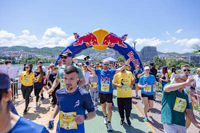 Participants cross under the Red Bull arch during the Wings For Life World Run app run in Tirana, Albania, on May 5, 2024, with vibrant energy and a supportive crowd