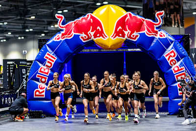 HYROX Elite 15 women charging forward under a Red Bull arch