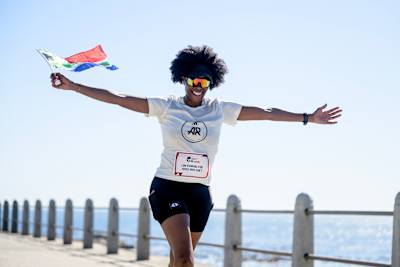 A Wings for Life World Run participant running in Cape Town, South Africa in 2025, proudly waving the flag.