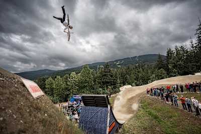 Erik Fedko performs a dramatic aerial trick at Red Bull Joyride 2025 in Whistler, BC, captivating the crowd and showcasing extreme mountain biking skill against a scenic mountain backdrop