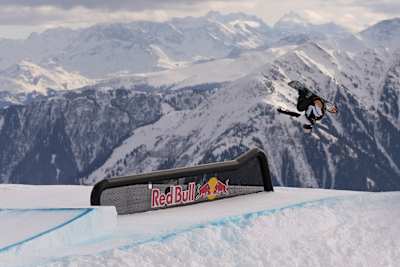 On January 16, 2026, snowboarder Romain Allemand catches air at the Laax Open in Laax, Switzerland, against a dramatic alpine backdrop.