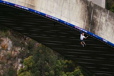 Thomas van Tonder hangs from monkey bars beneath Bloukrans Bridge during Red Bull Bridge Bars in South Africa in October 2026.