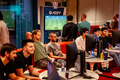Participants compete on EA Sports FC 27 at the Red Bull Wings Cup in Brussels, Belgium surrounded by gaming screens.