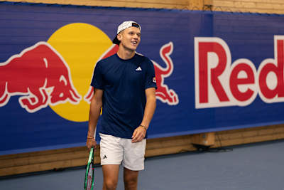 Jakub Menšík smiles with his tennis racket in front of a Red Bull backdrop in Prague, Czech Republic.