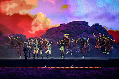 NewJeans perform alongside dancers at the League of Legends World Championship in Seoul, South Korea, on 19 November 2023, against a vivid rocky mountain backdrop.