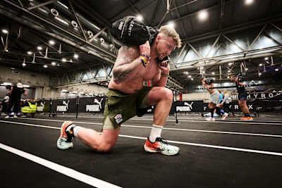 Participante de HYROX trabajando en la estación de estocadas con saco de arena