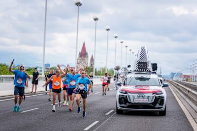Runners celebrate as the iconic Red Bull Wings for Life World Run Catcher Car approaches in Vienna, Austria during the thrilling 2025 event