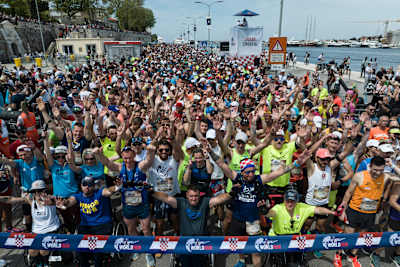 Une foule massive de coureurs et d'athlètes en fauteuil roulant lève les bras lors de la Flagship Run Wings for Life à Zadar, en Croatie, en mai 2023.