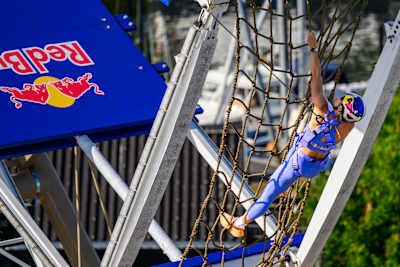 In Odense, Denmark, July 2026, Ida Mathilde Steensgaard tackles the Red Bull Ferris Wheel challenge, climbing a rope net in dynamic, branded gear for an action-packed event