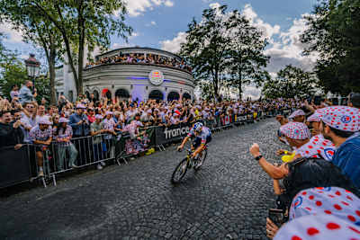 In 2026, Remco Evenepoel of Red Bull - BORA - hansgrohe races through the cheering crowds at the Le Tour de France finale in Montmartre, Paris, near Sacré-Cœur.