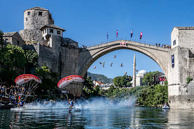 Skydivers Marco Waltenspiel and Marco Fuerst of Austria fly under Stari Most during a mass ive at the Red Bull Cliff Diving World Series in Mostar, 2023