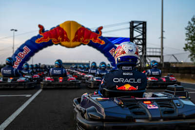 Red Bull Racing competitors line up for Max vs 100 at Silverstone, Great Britain, on 22 July 2026, with Max Verstappen’s kart and helmet leading the field beneath the Red Bull arch