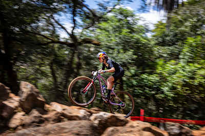 Kate Courtney competes at the 2025 UCI XCO World Cup in Araxa, Brazil, soaring through the forest on her mountain bike.