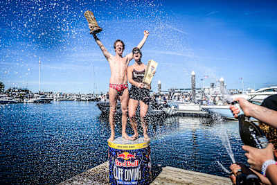 Rhiannan Iffland of Australia and Gary Hunt of France celebrate their 2025 Red Bull Cliff Diving World Series victories in Boston, USA, spraying champagne beside the water