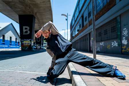 THE D Soraki dancing under a bridge with tagged walls.