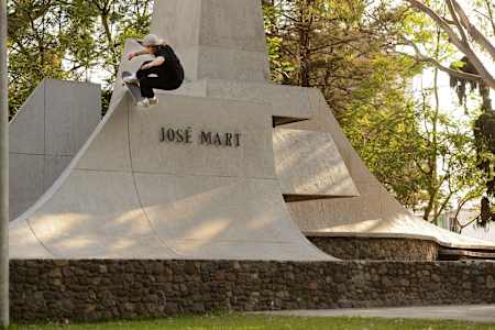 Jaakko Ojanen ist mit seinem Skateboard eine steinerne Skulptur, die geformt ist wie eine Seite einer Halfpipe, hochgefahren und hat es mittig im Rock to Fakie auf der Oberkante abgesetzt 