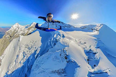 In 2024, Peter Salzmann soars in a wingsuit over snowy Swiss Alps during the Red Bull Wingsuit Foil Project.