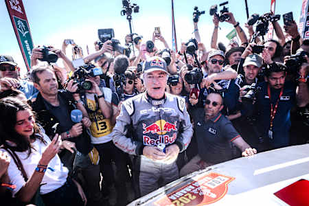 Carlos Sainz of Team Audi Sport celebrates his Rally Dakar 2024 victory in Yambu, Saudi Arabia, surrounded by photographers.