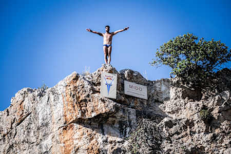Carlos Gimeno aus Spanien bereitet sich auf den Tauchgang beim ersten Stopp der Red Bull Cliff Diving World Series 2024 am Vouliagmeni-See in Athen, Griechenland, am 24. Mai 2024 vor.  
