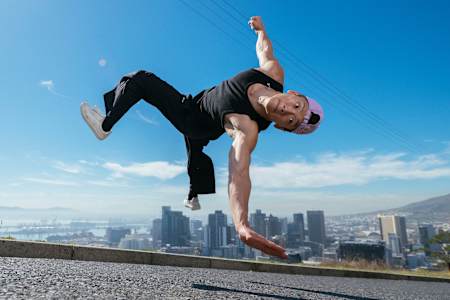 În 2024, B-Boy Phil Wizard execută o acrobație de înghețare în aer pe fundalul orașului Cape Town