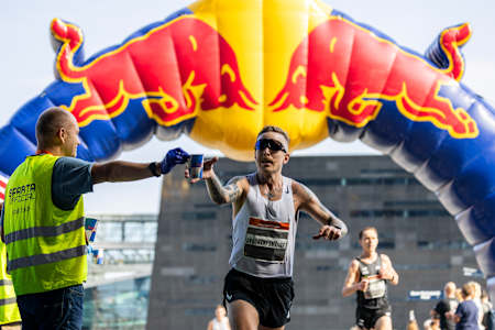 Läufer beim Kopenhagener Halbmarathon in Dänemark unter einem aufblasbaren Red Bull-Bogen.