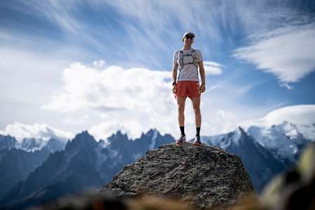 Im Jahr 2022 steht Tom Evans auf einem Felsvorsprung mit Blick auf die schneebedeckten Gipfel in Chamonix, Frankreich.