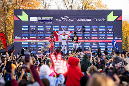 El 11 de octubre de 2025, los ganadores celebran en el podio masculino de la UCI Mountain Bike World Cup en Mont-Sainte-Anne, Canadá, rodeados por una enérgica multitud de Red Bull.