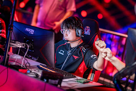 T1 esports team member gears up for intense competition at Red Bull Home Ground 2024 in Berlin, Germany, shown celebrating a team play with a fist bump.