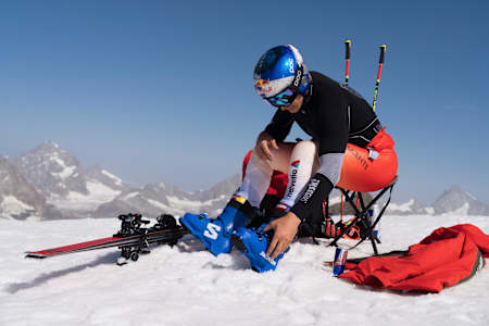 Swiss skiing star Marco Odermatt prepares at a 2025 training camp in Zermatt, Switzerland, surrounded by snowy Alpine peaks and dynamic ski equipment