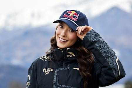 Eileen Gu showcases her signature Red Bull cap and custom jacket in Wanaka, New Zealand, during a dynamic 2025 portrait session set against breathtaking mountain scenery.