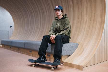 Yuto Horigome sits with a skateboard inside a modern venue in Tokyo, Japan.