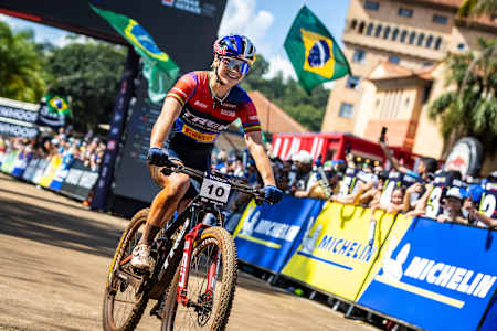 Evie Richards rides through the vibrant venue of Araxa, Brazil, during the UCI XCO World Cup on April 12, 2025, capturing the energy of international mountain bike racing.