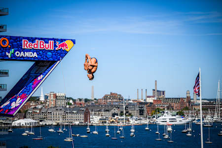 James Lichtenstein of the USA performs a dramatic mid-air dive from the 27 metre platform at the Institute of Contemporary Art during the Red Bull Cliff Diving World Series 2025 in Boston