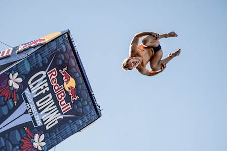 James Lichtenstein of the USA launches from the 27-metre platform at Boston's Red Bull Cliff Diving World Series 2025 final, capturing thrilling aerial acrobatics against the clear sky