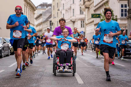 Läufer und ein Rollstuhlfahrer rasen beim Wings for Life World Run 2025 durch Wien und bringen Red Bulls Geist der Inklusivität und Energie auf die Straßen der Stadt