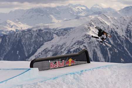 On January 16, 2026, snowboarder Romain Allemand catches air at the Laax Open in Laax, Switzerland, against a dramatic alpine backdrop.